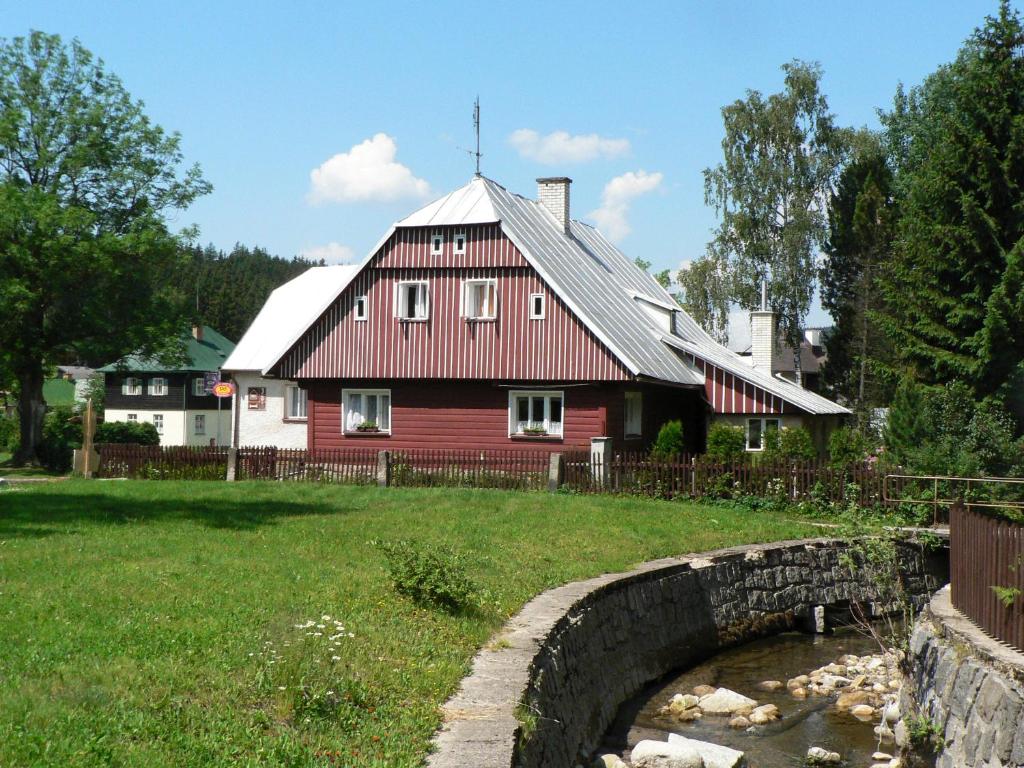 a red house with a bridge in front of it at Penzion Pod můstky in Harrachov