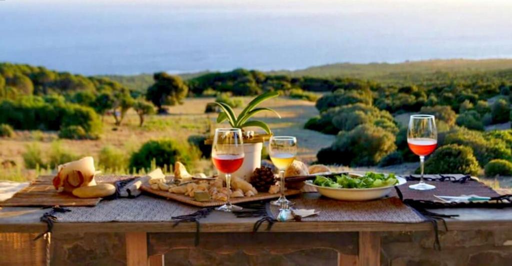 a table with wine glasses and a plate of food at Charming house with sea and mountain views in El Chaparral in EL Chaparral
