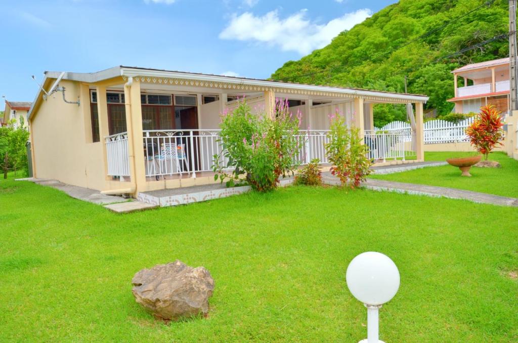 a house with a yard with a ball on the lawn at Studio cocooning à Saint Anne / 27 m² / jardin fleuri in Sainte-Anne