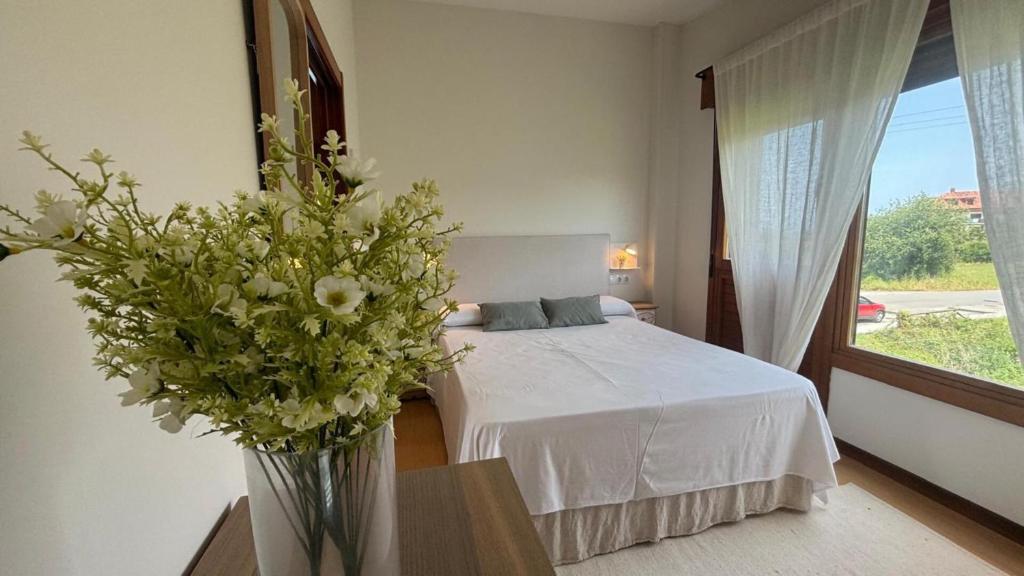 a bedroom with a bed and a vase of flowers at AP TXALUPA II in Barro de Llanes