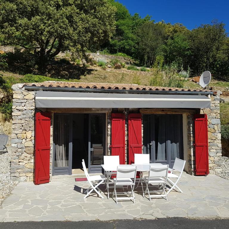 a table and chairs in front of a building with red doors at Maison confortable avec piscine à Saint-Julien-de-la-Nef in Saint-Julien-de-la-Nef