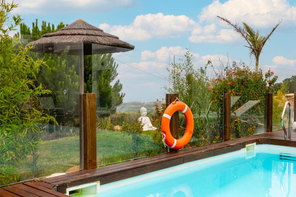 a swimming pool in a garden with an orange life preserver at Penedo Escape Sea Suites in Colares