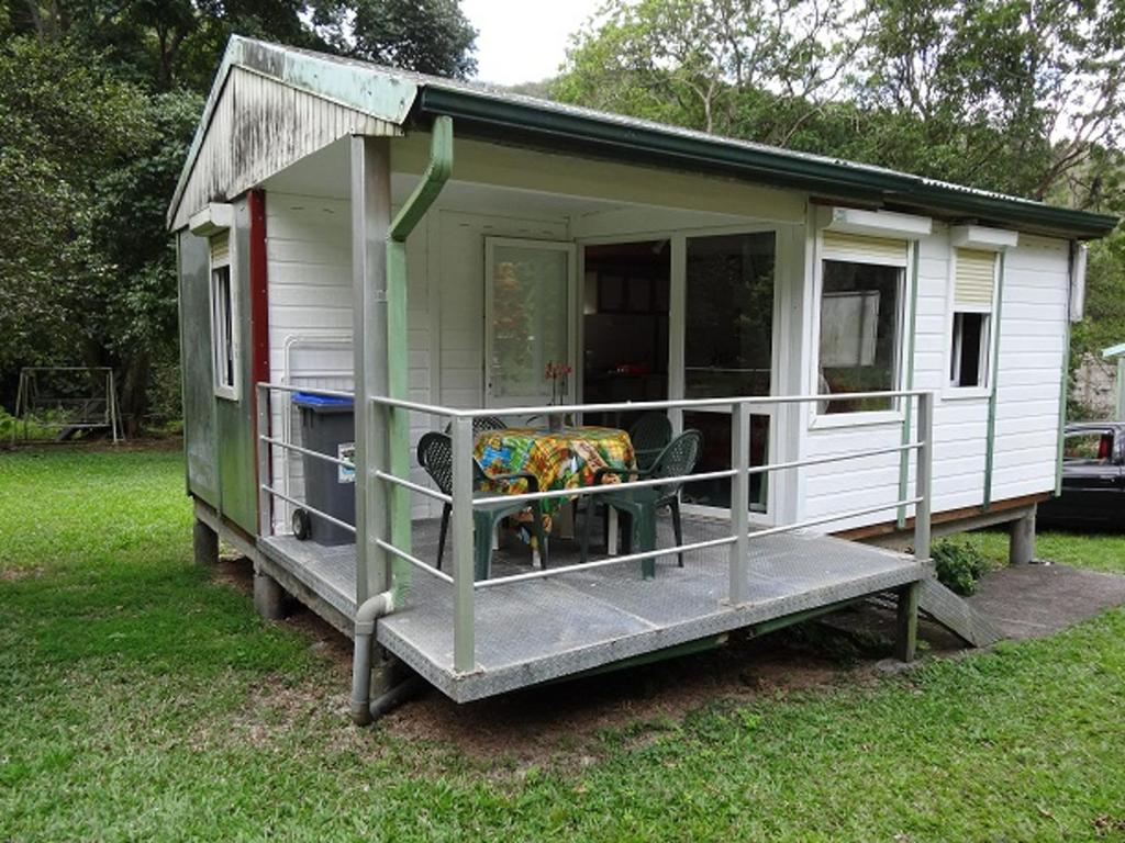 a green and white tiny house with a porch at Bungalow Charmant à Pointe-Noire in Pointe-Noire