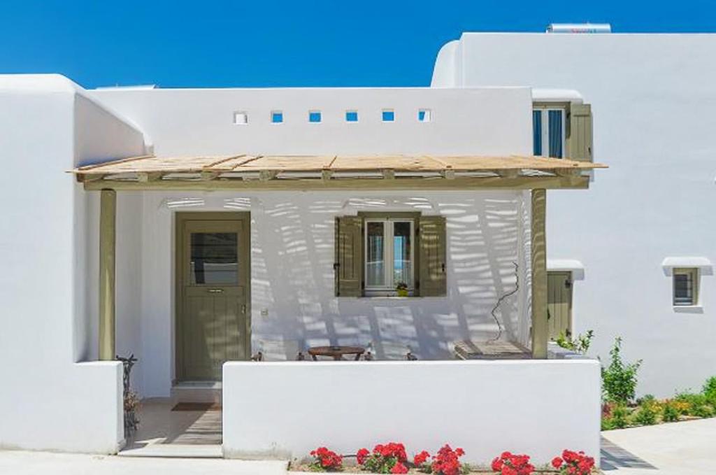 a small white house with a porch and flowers at Spacious house with sea view in Ag. Arsenios, garden in Glinádhon