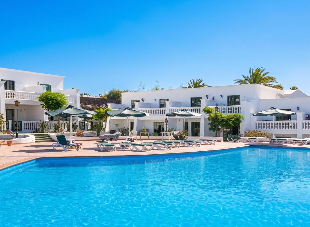 a pool in front of a hotel with chairs and umbrellas at Charming Apartment in Tías + Pool in Tías