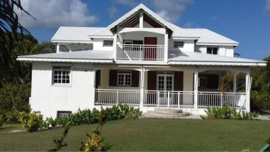 a large white house with a large yard at Appartement charmant à Petit-Canal in Petit-Canal