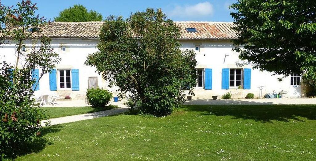 a white house with blue windows and a yard at Maison de charme à Saint-Vincent-la-Châtre avec piscine partagée in Saint-Vincent-la-Châtre