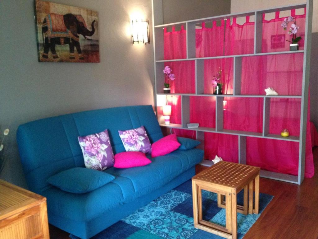 a living room with a blue couch and pink shelves at Studio charmant Le Moule 35m² + balcon in Le Moule