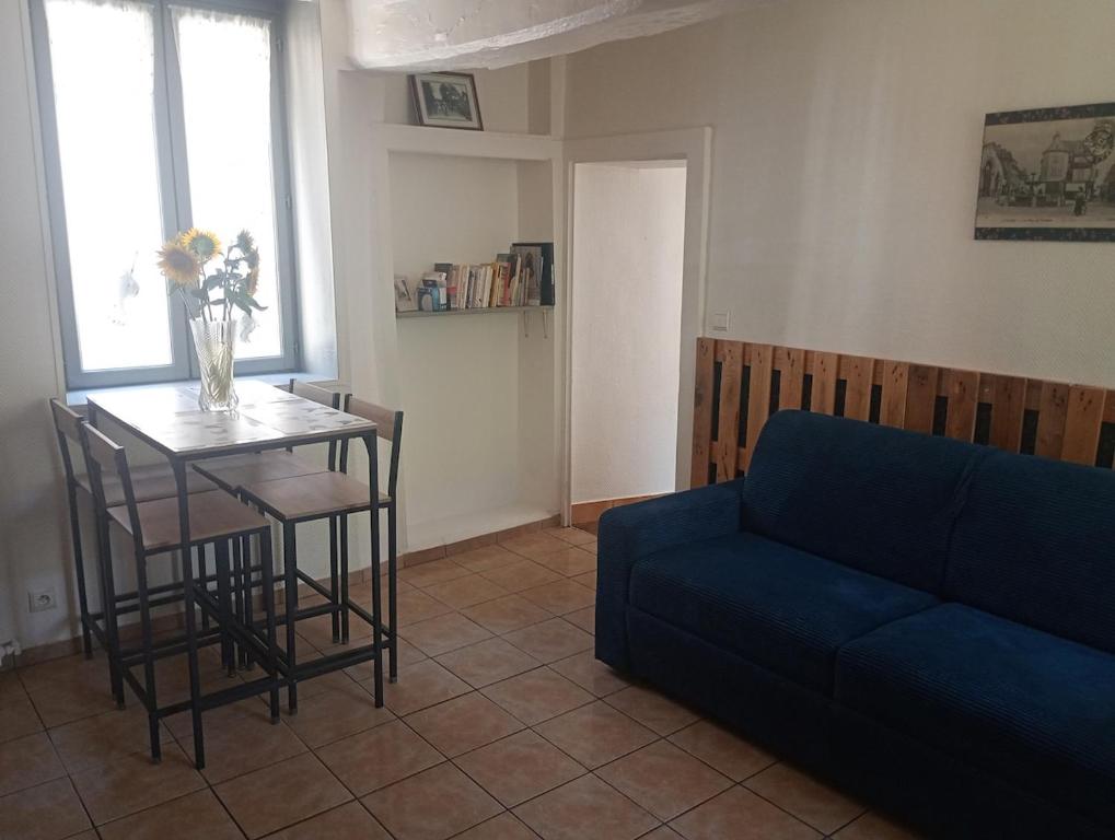 a living room with a blue couch and a table at La maisonnette Poyaudine in Toucy