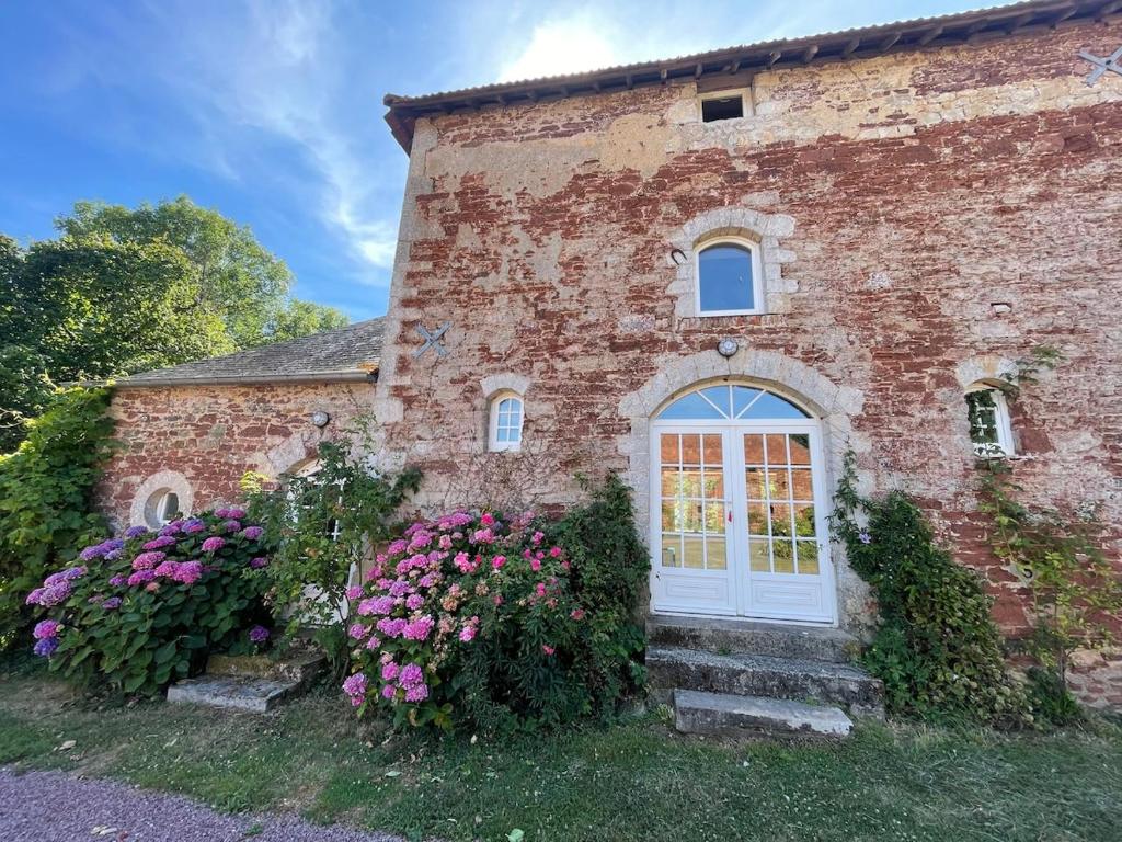 a brick building with a white door and flowers at Cottage Normand in Lison