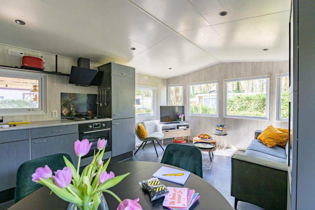 a kitchen and living room with a table and chairs at De Bosvlinder in Hoenderloo