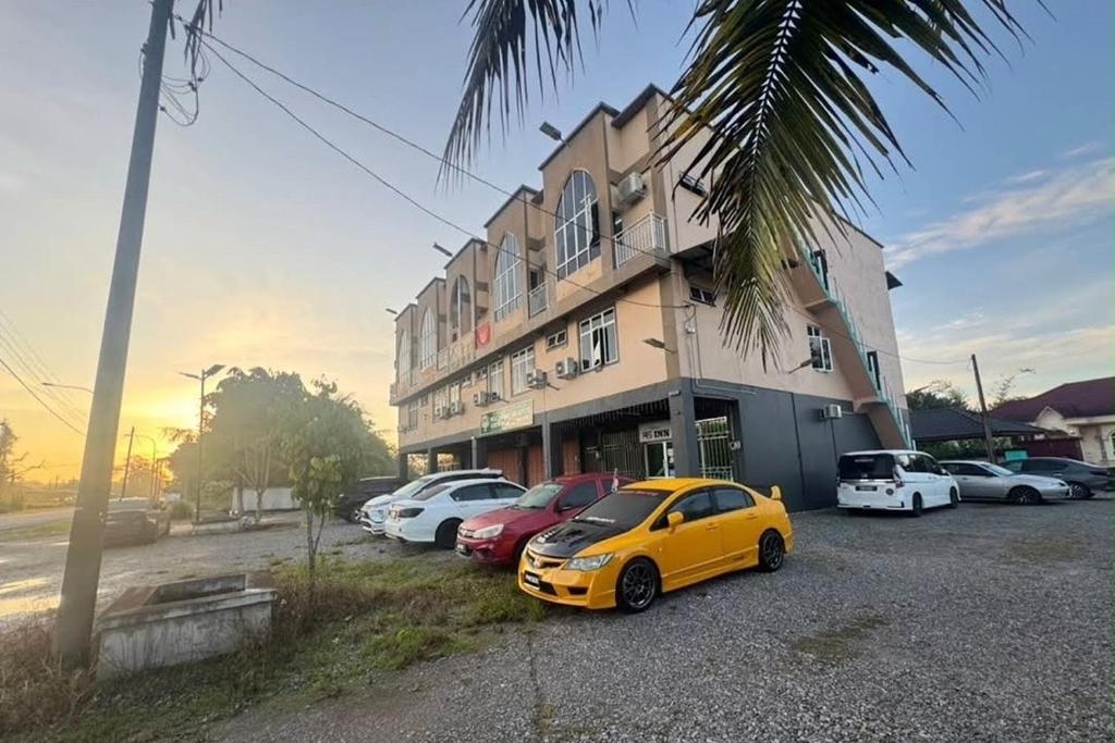 a yellow car parked in a parking lot in front of a building at Hotel RS Inn in Rantau Panjang