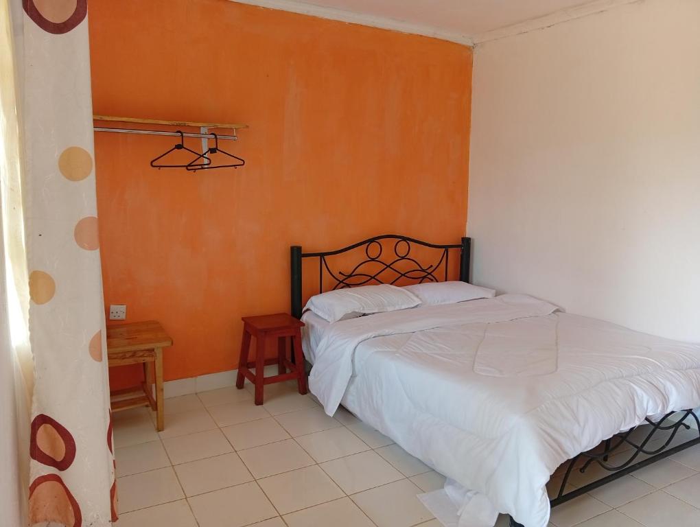 a bedroom with a bed and an orange wall at Lago Resort - Kakamega Forest in Kakamega