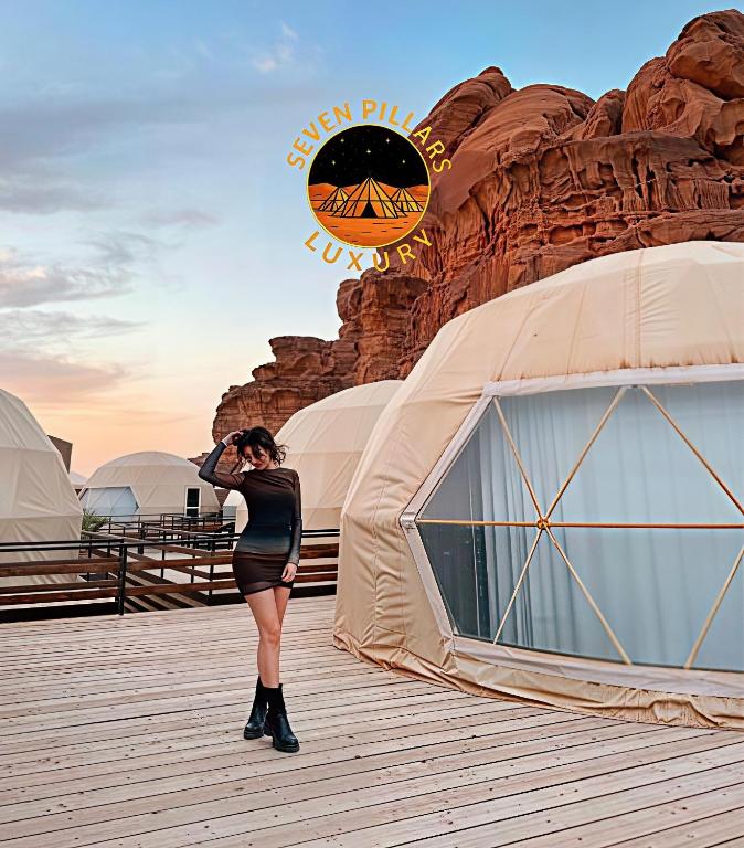 a woman standing on a boardwalk next to a tent at SEVEN PILLARS lUXURY CAMP in Wadi Rum