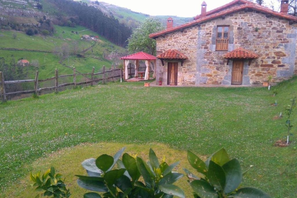 a stone house in a field with a fence at Charming House in La Cavada with Jacuzzi in La Cavada
