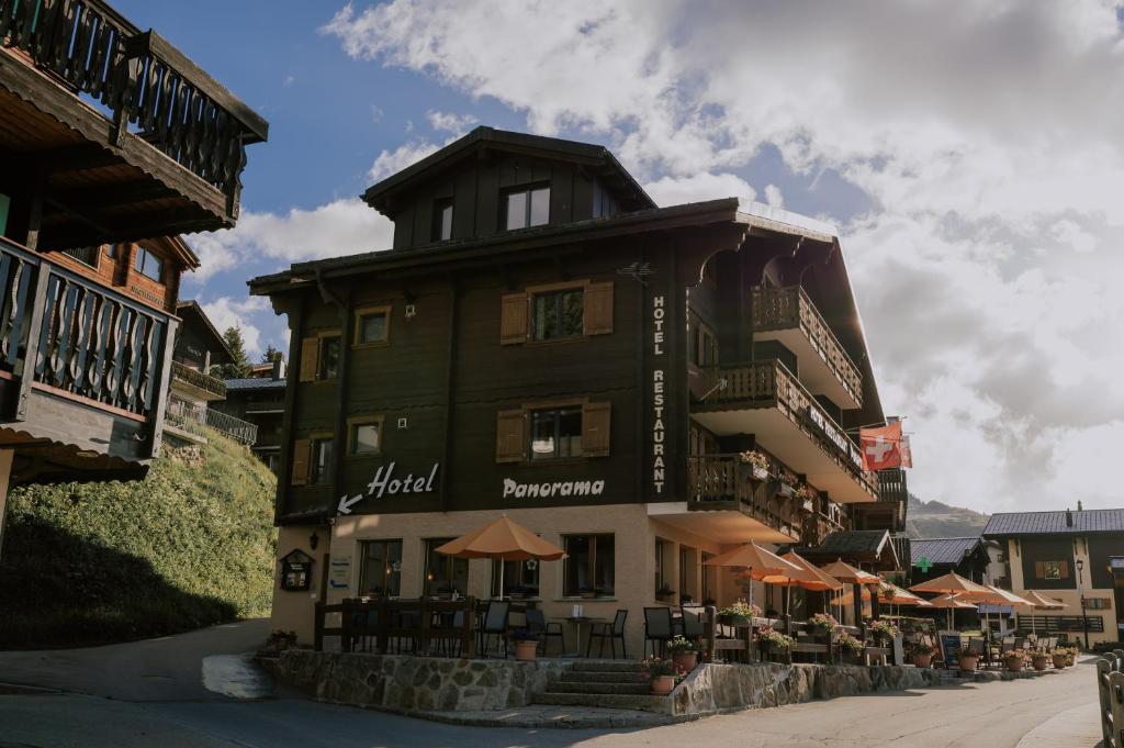 a building with tables and umbrellas on a street at Panorama Hotel & Restaurant in Bettmeralp