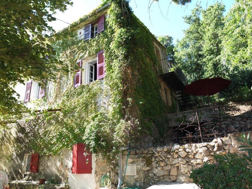 an ivy covered house with red doors and red windows at Appartement raffiné à Feliceto - 120 m² avec vue sur montagne in Feliceto