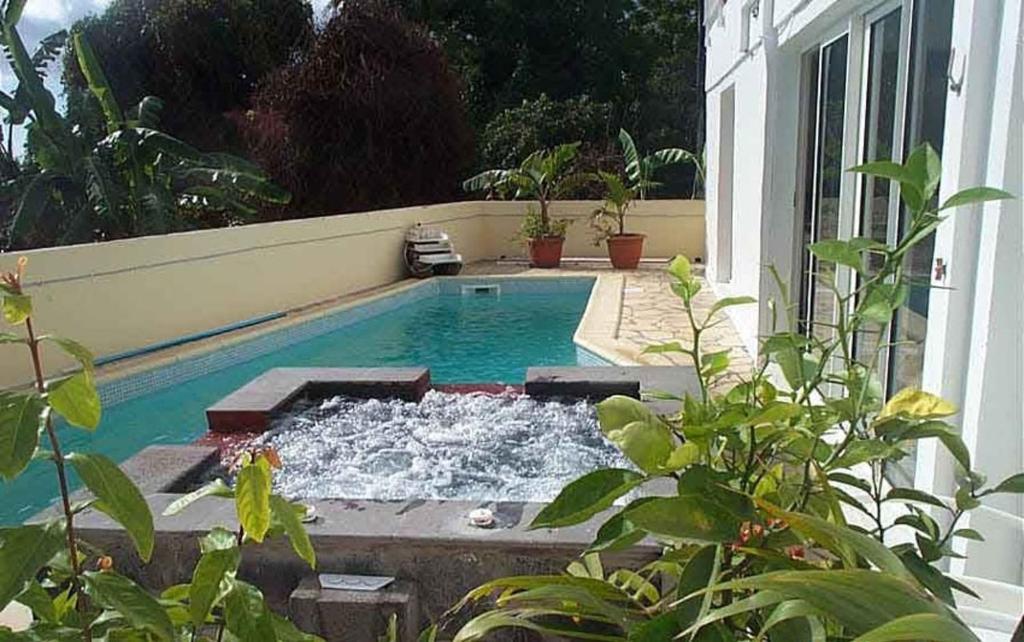 a pool with water in the middle of a house at Appartement spacieux à Bois des Nèfles, 70 m², piscine partagée in Le Bois de Nèfles