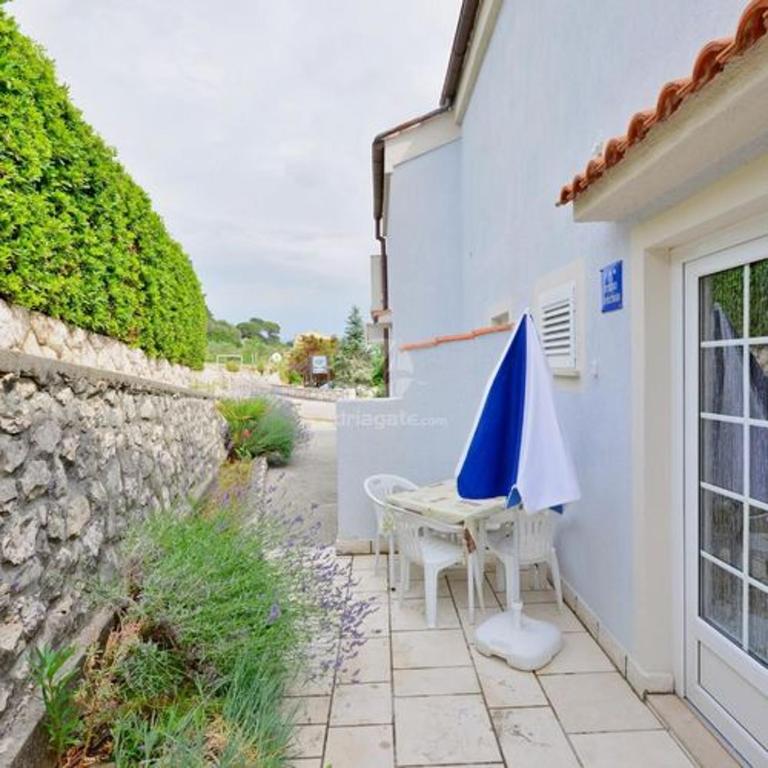 a patio with an umbrella and a table and chairs at Charming apartment in Kampor with private garden - 28 m² in Kampor