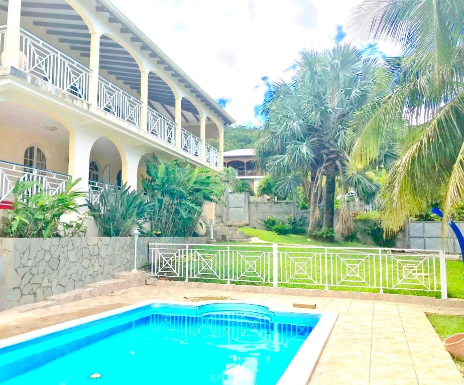 a swimming pool in front of a house with palm trees at Spacieuse villa à Deshaies avec piscine privée in Deshaies