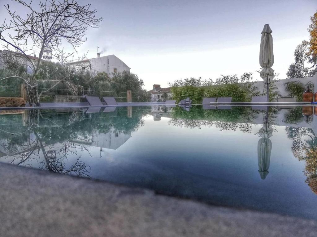 a pool of water with an umbrella and chairs at Picturesque Villa in Santo António das Areias with Private Pool in Marvão