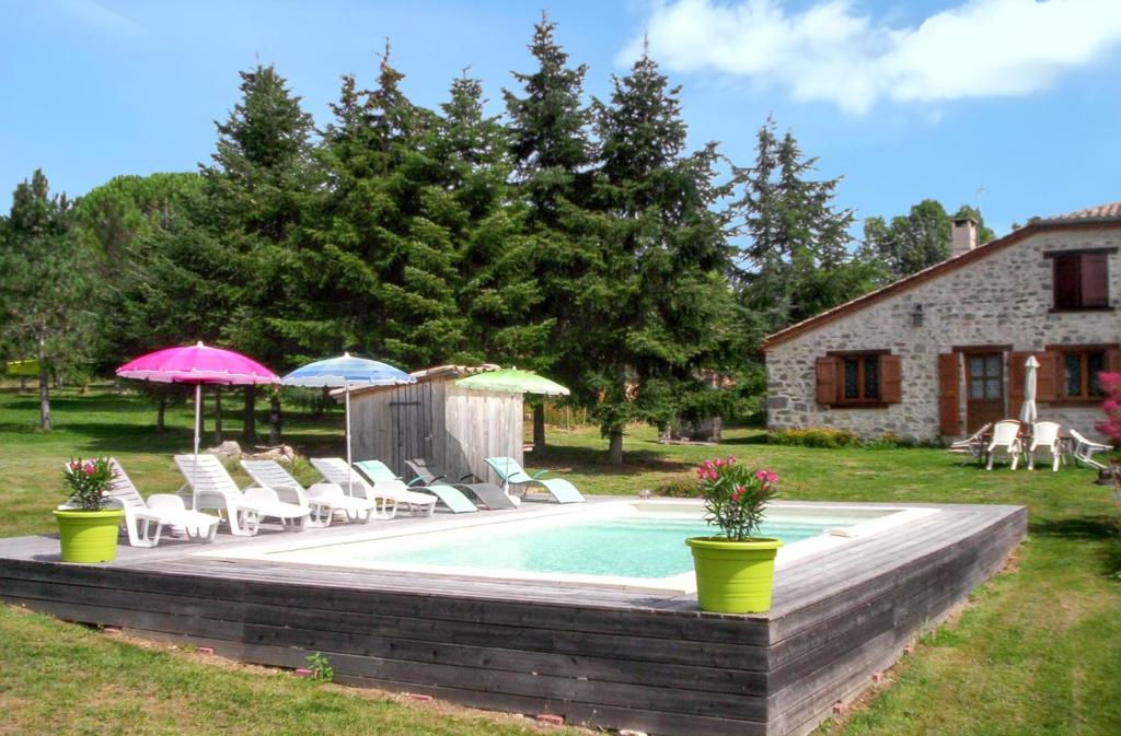 a pool with chairs and umbrellas next to a house at Maison charmante à Saint-Cirq avec piscine privée in Saint-Cirq