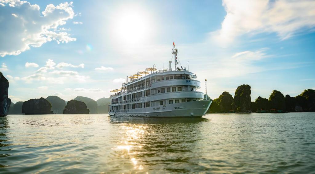 a cruise ship on the water with limestone islands in the background at The Au Co Cruise - Longest Cruise 2 Bays in Ha Long