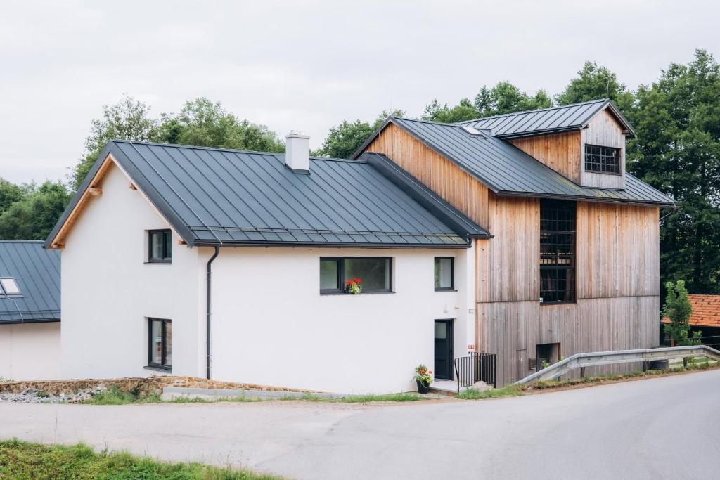 a barn style house with a black roof at Penzion Mlýn Cibotín in Česká Bělá