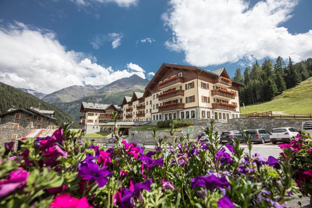 a large building with purple flowers in front of it at Hotel Residence 3 Signori in Santa Caterina Valfurva