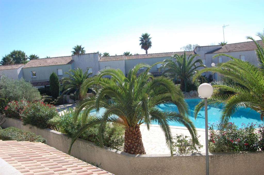 a resort with a palm tree and a swimming pool at Appartement cosy à Valras-Plage / 48m² / Piscine partagée in Valras-Plage