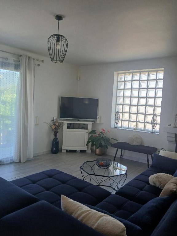 a living room with a blue couch and a flat screen tv at les Trois Cœurs in Mison