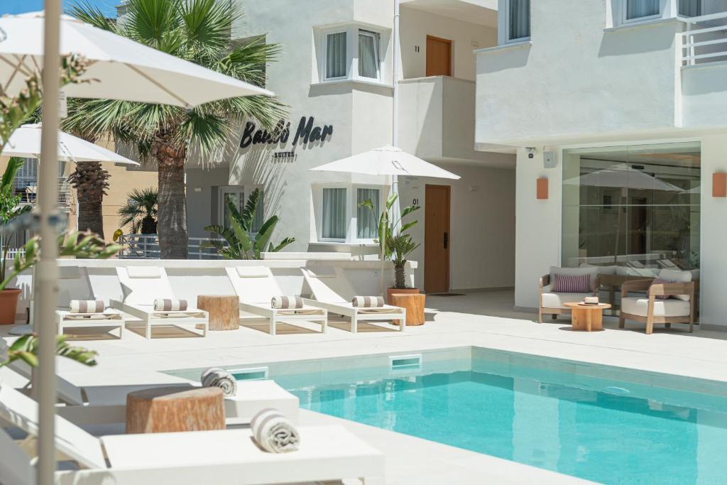a pool with chairs and umbrellas next to a building at Bauló Mar Apartments in Can Picafort