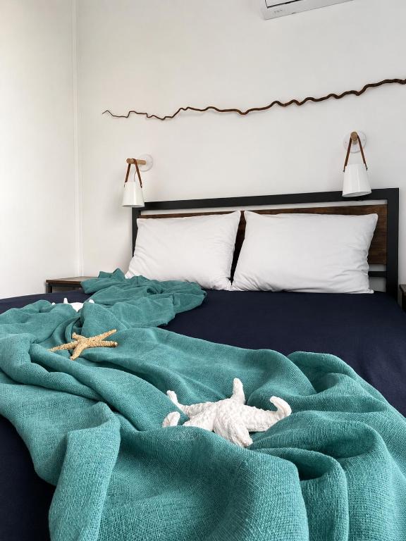 two stuffed animals laying on a green blanket on a bed at Alta Vista Apollonia Sunset in Sozopol