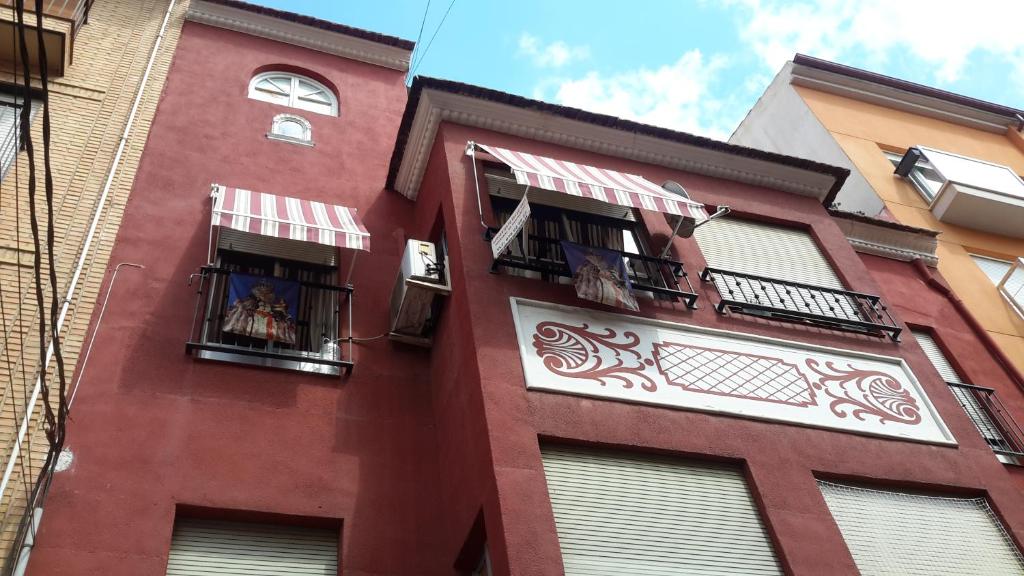 un edificio alto de color rojo con ventanas y balcones en Arrabal de San Benito II, en Murcia