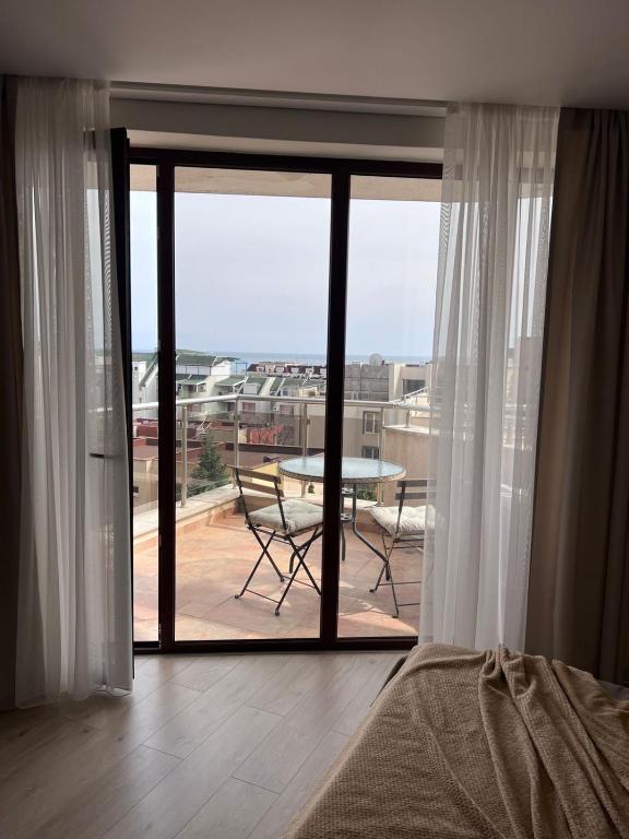 a bedroom with a view of a balcony with a table at Millennium Apart Complex in Sveti Vlas