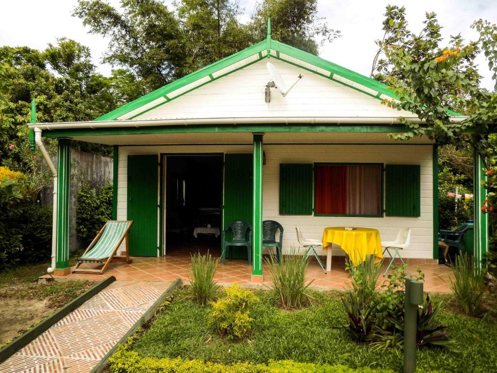 a green and white house with a patio at Charming house with sea view in Foulpointe + Enclosed garden. in Foulpointe