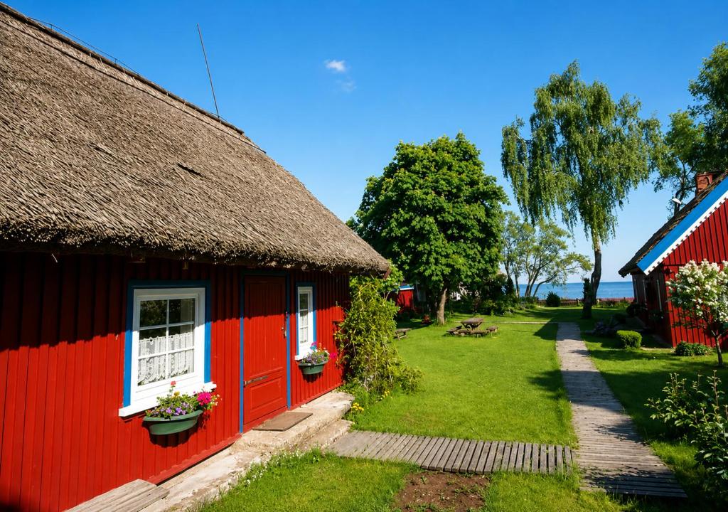 a red house with a thatched roof and a yard at Authentic Fisherman House in Preila