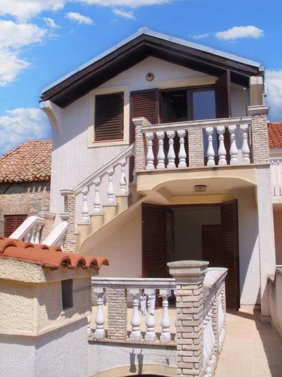 a white house with stairs and a balcony at Spacious Apartment in Zlarin + terrace in Zlarin