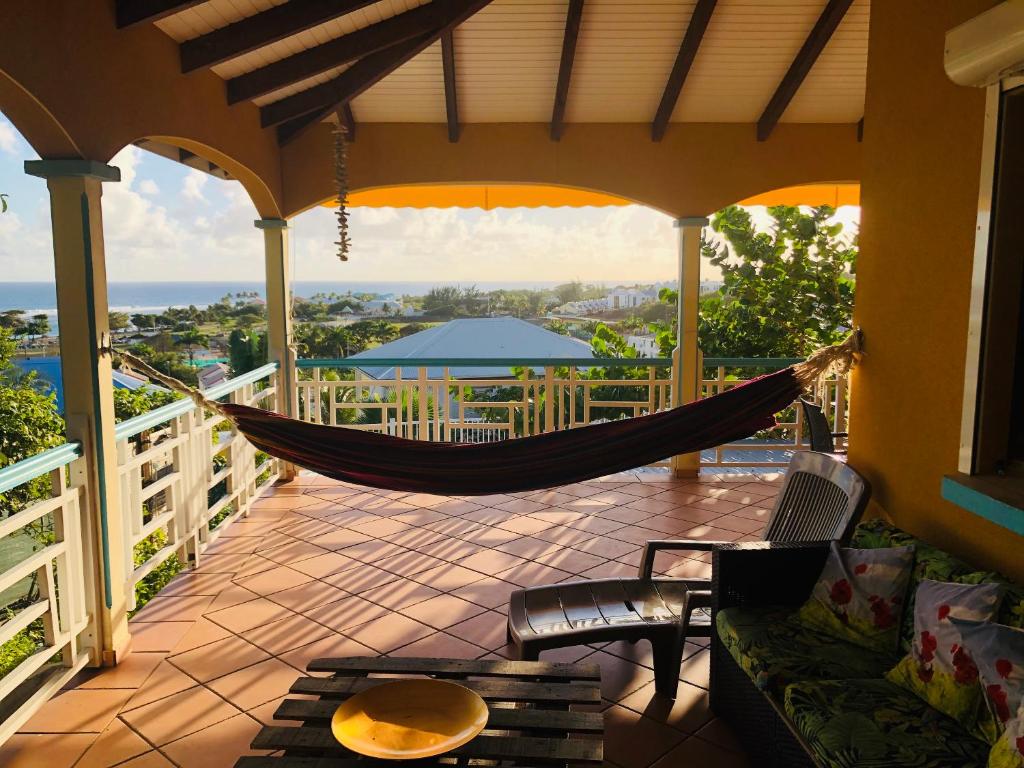 a hammock on a porch with a view of the ocean at Appartement spacieux à Saint-François 150 m² avec piscine partagée ! in Saint-François