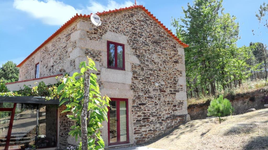 a small stone house with red doors and windows at Cozy House in Seia with Fireplace in Faia