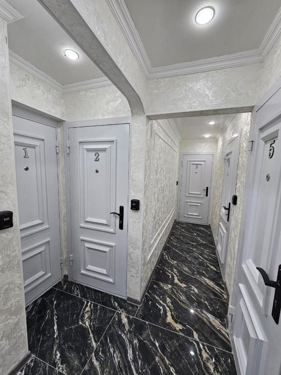 a hallway with two white doors and marble floors at Престиж 2 номер in Shymkent