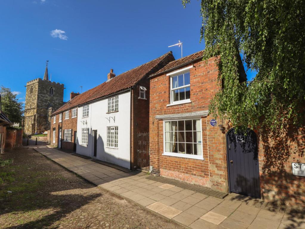 an old brick building with a church in the background at Hangmans cottage in Horncastle