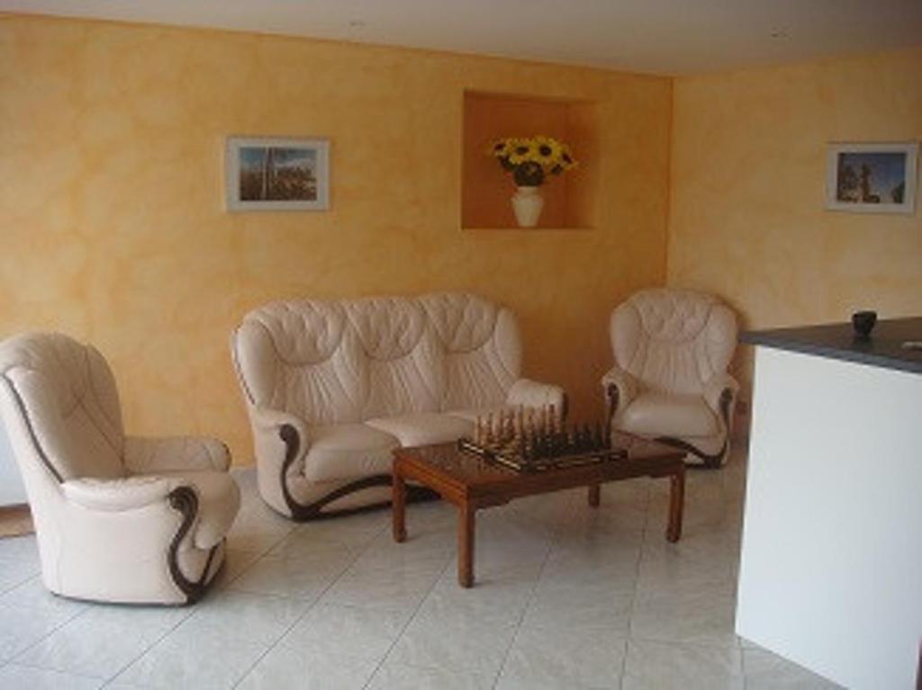 a living room with two white chairs and a table at Maison charmante en campagne à Mouterre-Silly, Jardin, Terrasse. in Mouterre-Silly