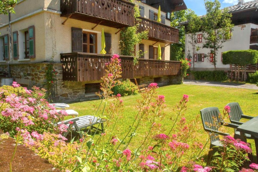 a garden with pink flowers in front of a house at Appartement confortable à Megève | 46m² | Vue sur montagne in Megève