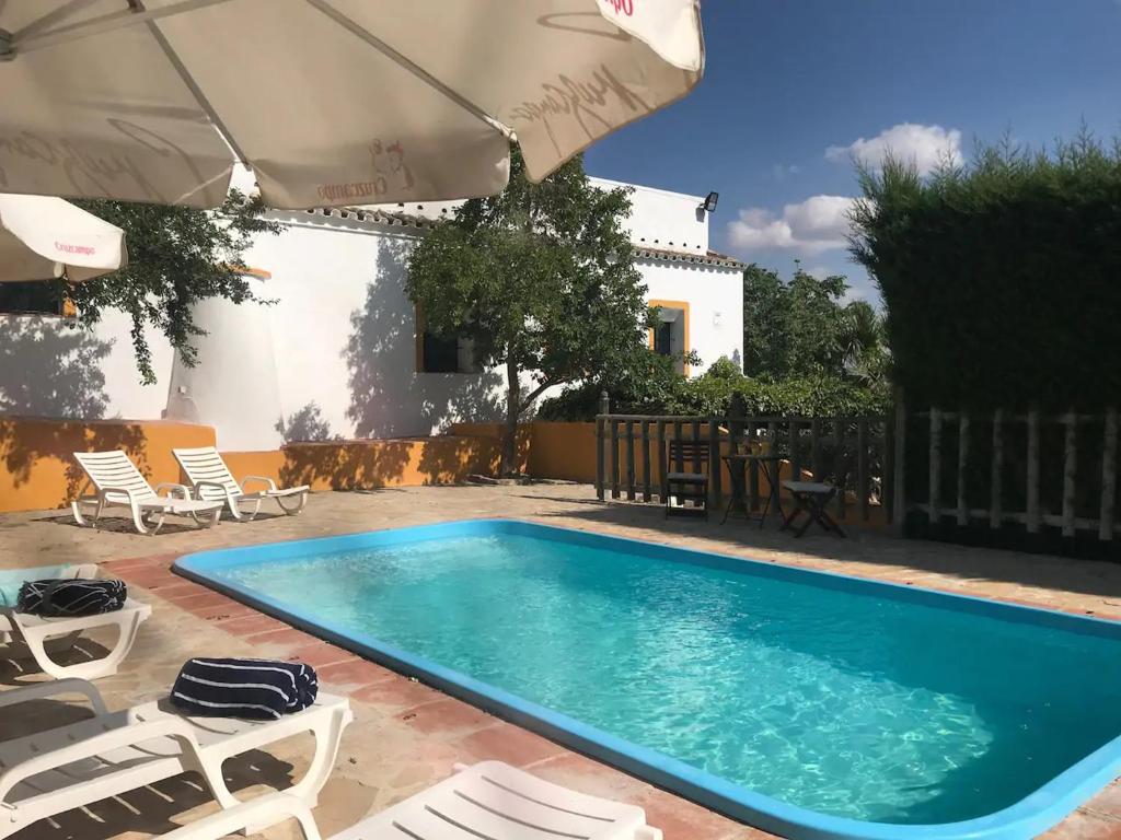 a swimming pool with chairs and an umbrella at Elegant Villa in El Saucejo with Private Pool in Saucejo