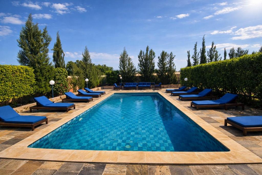 a swimming pool with blue lounge chairs and a resort at Riad les trois merveilles in Essaouira