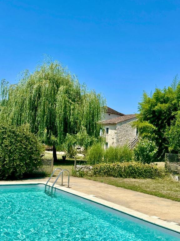 a swimming pool in a yard with a tree at Les Foucauds in Saint-Quentin-de-Caplong