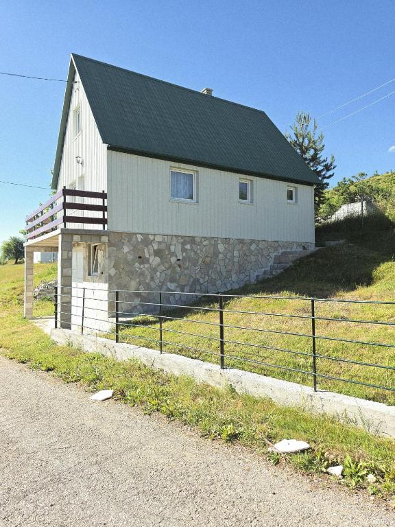 a white barn with a black roof on a field at Cottage in nature Bare, Savnik in Šavnik