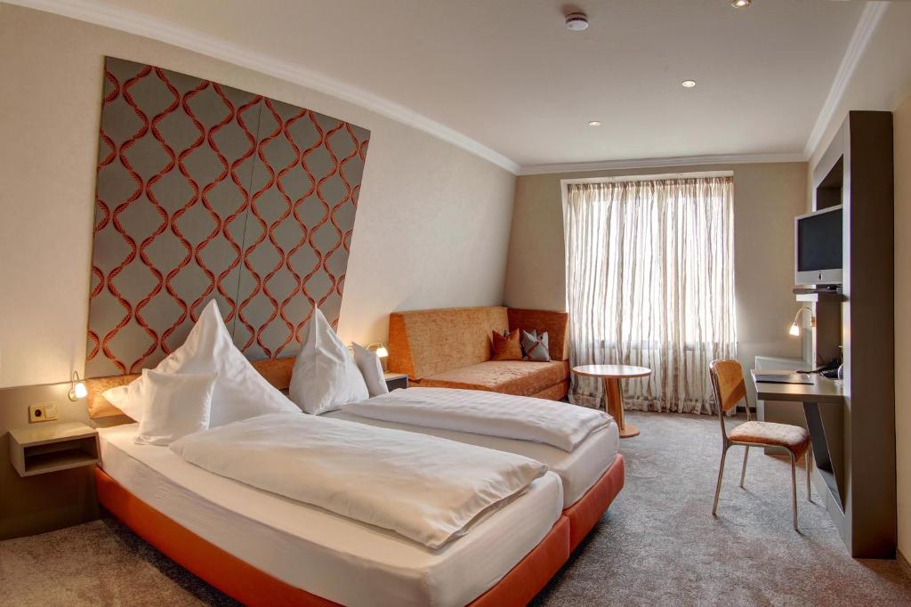 ヴァーレンドルフにあるHotel Im Engelの大きなベッドとデスクが備わるホテルルームです。
