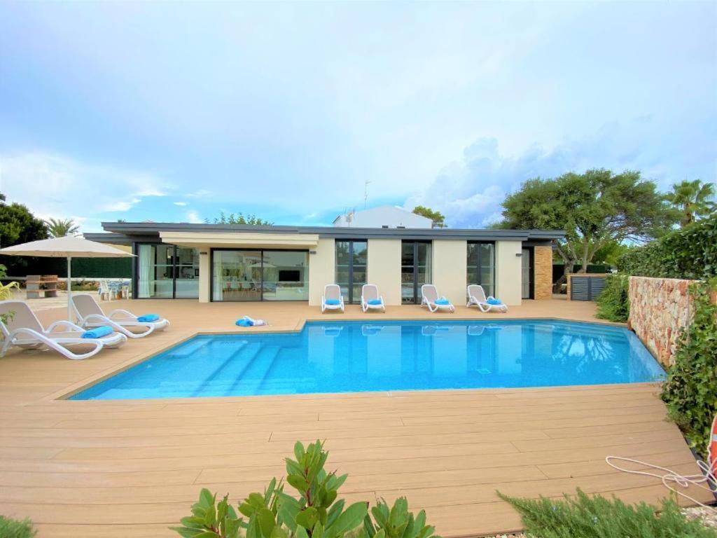 a swimming pool with chairs and a house at Villa LUCIA in Cala en Blanes